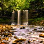 Sgwd yr Eira or Fall of Snow. A low to the river shot upstream with the falls head on and the sun creating a golden glow off the rocks and water.